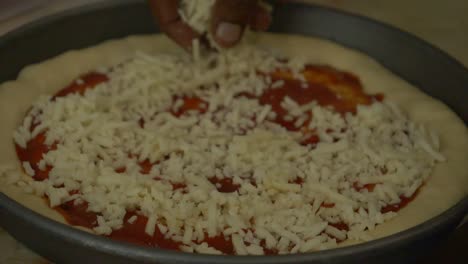 Hand-Sprinkling-Cheese-On-Pizza-Base