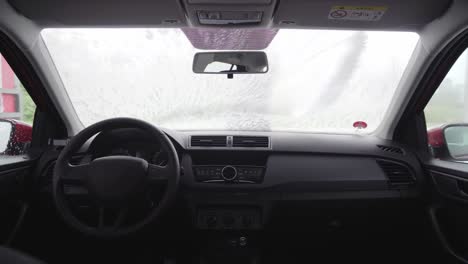 Car-wash-interior-view-of-man-and-windscreen-full-of-white-foam-from-high-pressure-cleaner