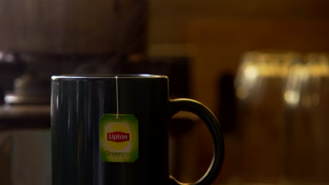 Lipton-green-tea-bag-in-a-cup-of-hot-water-steam-closeup