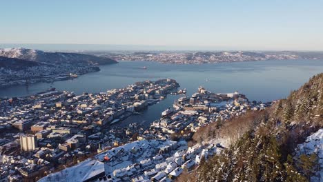 Aerial-shot-over-Bergen-Cityscape-from-hillside-mountain-with-snow---Norway