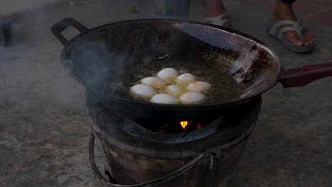 Motion-Chef-uses-spatula-to-add-duck-eggs-on-rusty-frying-pan-outdoors---Street-food