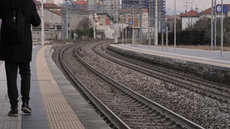 Vista-Trasera-Del-Hombre-Caminando-Cerca-De-Los-Rieles-Del-Tren-En-La-Estación