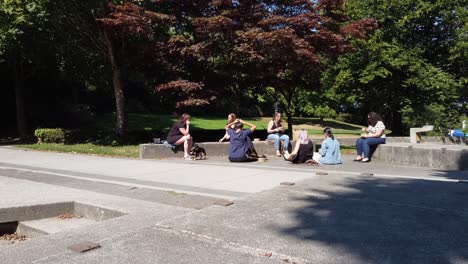 2-2-Friends-not-social-distancing-during-Coronavirus-Covid-19-pandemic-masks-not-being-worn-closely-seating-with-each-other-on-a-hot-summer-afternoon-at-a-modern-park-where-they-ignore-the-city-law