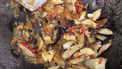 Stirring-stir-fried-sea-snail-dish-in-wok-with-spatula,-close-up