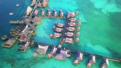 Aerial-flight-over-crystal-clear-water-and-resort-in-Malaysia,-close-distance-shot-moving-above-in-slow-motion