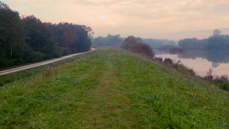 Path-with-lake-view-and-a-single-road-bordering-it-at-foggy-autumn-morning-in-Central-Europe