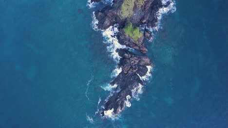 Aerial-tracking-shot-of-deep-blue-ocean-and-dark-cliffs-with-green-vegetation-in-the-Philippines
