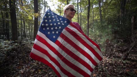 Pretty-blonde-woman-wrapping-herself-in-a-flag-as-camera-orbits-around-her-in-a-forest