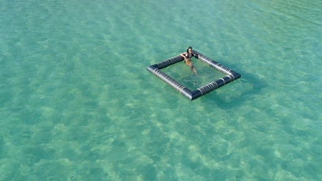 beautiful-girl-sitting-and-tanning-in-a-floating-device-in-the-ocean,-Koh-Kood,-Thailand