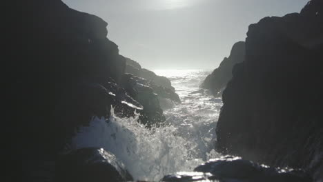 Slow-motion-low-angle-close-up-shot-of-an-ocean-waves-splashing-on-rocks-close-to-camera