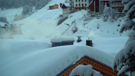 Ein-Rauchender-Schornstein-Auf-Dem-Schneebedeckten-Dach-Im-Dorf-Samnaun,-Schweiz