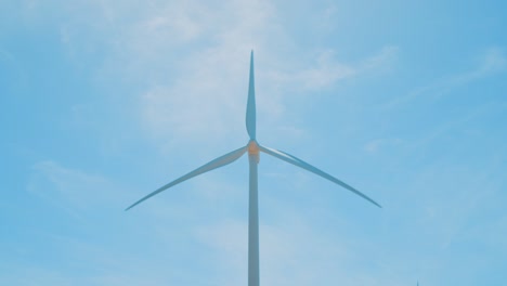 Wind-turbine-spinning-and-generating-clean-energy-with-blue-sky-background