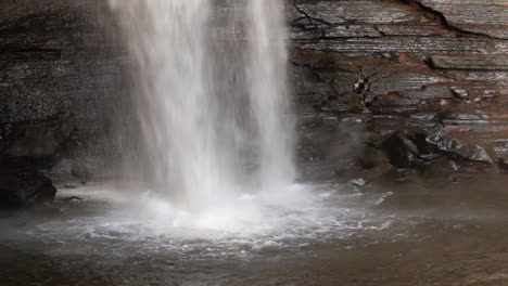 Nahaufnahme-Eines-Wasserfalls,-Der-über-Eine-Klippe-Fließt-Und-In-Ein-Becken-Am-Fuß-Plätschert