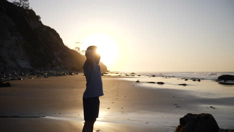 A-strong-man-in-silhouette-breathing-and-stretching-after-an-early-morning-run-and-workout-on-the-beach-at-sunrise-in-Santa-Barbara,-California-SLOW-MOTION