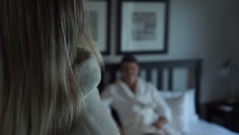 SLOWMO---Young-attractive-blond-female-brushing-hair-and-male-lying-on-bed-in-luxury-boutique-hotel-room