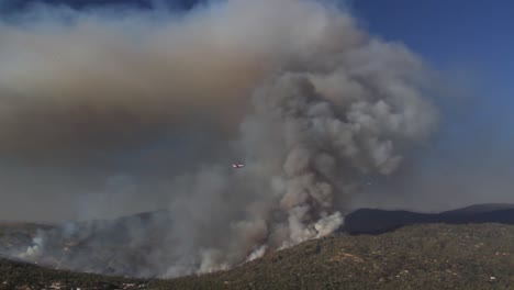 Footage-of-plane-flying-through-smoke-plume-of-California-wildfire-spreading-across-mountains