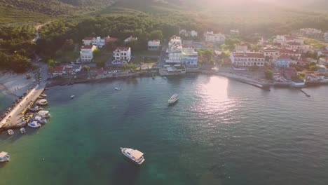 Aerial:-Small-fishing-town-with-Greek-flag-on-Samos-island,-Greece