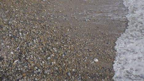 Waves-coming-in-and-out-on-stony-beach-in-slow-motion