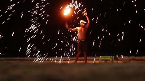 A-thai-man-spins-the-burning-steel-wool-with-his-one-arm,-coming-closer-to-the-crowd-and-creating-countless-amounts-of-bright-little-sparks-spinning-around-him-in-the-dark-night