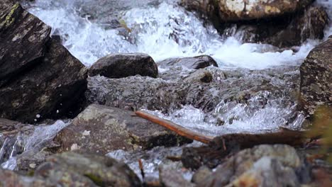 Slow-motion-of-a-wild-mountain-stream-flowing-through-the-rocks,-close-up-shot