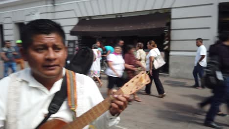 Closeup-on-faces-of-three-guitar-mariachi-singing-and-playing-their-guitars-outdoors-at-a-festival-in-Merida,-Mexico