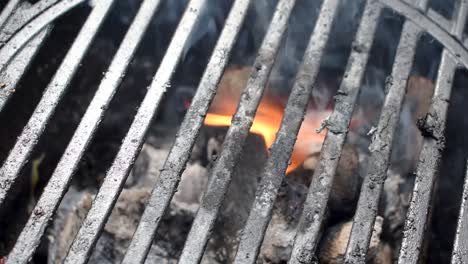 outdoor-grill-bars-closeup-showing-flames-and-smoke-from-buring-charcoal