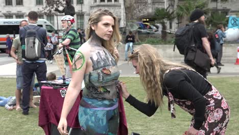 A-woman-has-her-body-painted-as-part-of-the-extinction-rebellion-protest-on-Parliament-Square,-London,-UK