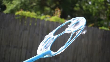 slow-motion-bubble-wand-creating-multiple-rainbow-bubbles-and-popping-outside