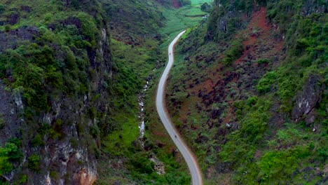 A-motorcycle-travels-on-a-road-in-a-deep-valley-that-cuts-through-a-mountain-in-northern-Vietnam
