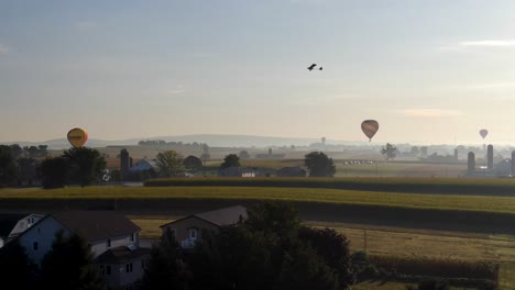 Aerial-drone-view-of-Hot-Air-Balloons-in-Amish-Country,-Pennsylvania-with-Powered-Paraglider-flying