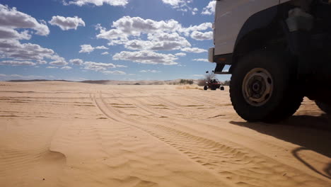 4x4-overland-expedition-truck-and-dune-buggy-driving-in-sand-desert-in-California,-slow-motion