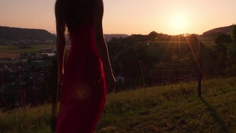 Eine-Frau-In-Einem-Roten-Kleid-Betrachtet-Den-Sonnenuntergang-In-Einer-Landschaft