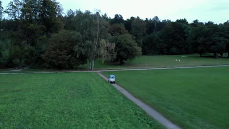 Orbital-aerial-drone-shot-following-light-electric-vehicle-driving-on-cycle-path-in-Zürich,-Switzerland