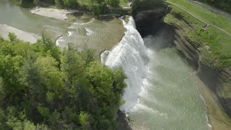 Drone-shot,-flying-around-a-waterfall,-while-panning-down