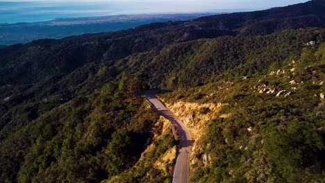 Cyclist-rides-down-Mountain-Road-in-Santa-Barbara-at-Dawn,-Drone-Chase