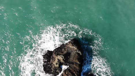 Drone-flies-over-sea-stack-in-water