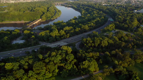 Aerial-drone-reveal-of-Philadelphia-skyline-and-Schuylkill-River-with-cars-and-traffic-during-a-warm-summer-sunset