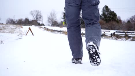 Low-angle-view-of-man-walking-on-snow-covered-trail-in-slow-motion