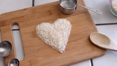 Grano-De-Arroz-Blanco-En-Un-Corazón-Con-Utensilios-De-Cocina-E-Ingredientes-En-Una-Cocina