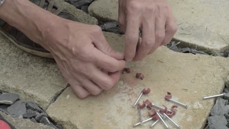 Workman-hands-preparing-nails-with-nail-hook-cable-clip-on-concrete-floor