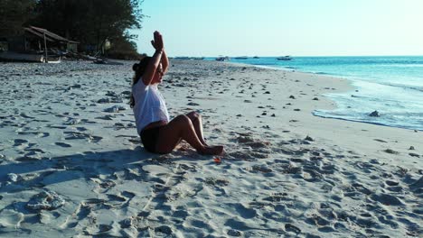 Young-woman-doing-Yoga-exercise-on-white-sand-of-exotic-beach-in-front-of-calm-sea-at-sunrise,-Philippines