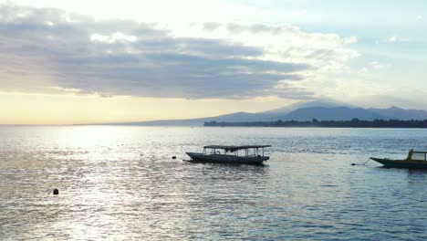 Verankerte-Boote,-Die-In-Der-Nähe-Der-Küste-Einer-Tropischen-Insel-Unter-Dem-Sonnenlicht-Des-Leuchtenden-Himmels-Bei-Wunderschönem-Sonnenuntergang-In-Indonesien-Schwimmen