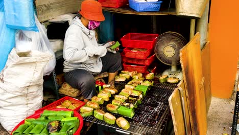 Mujer-De-Saigón-Asando-Comida-Callejera-Envuelta-En-Hojas-De-Plátano-En-Ho-Chi-Minh,-Vietnam---Cerrar-Cámara-Lenta