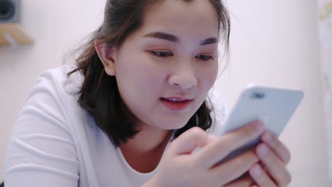 Schöne-Asiatische-Frau,-Die-Ihr-Smartphone-Betrachtet-Und-Berührt,-Entspannen-Sie-Sich,-Genießen-Sie-Und-Lächeln-Sie-Mit-Online-Social-Media-Im-Schlafzimmer