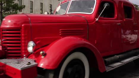 Vintage-red-vehicle,-old-fire-engine-equipped-with-tools-for-firefighting-tasks,-driving-on-city-street