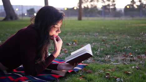 Eine-Hispanische-Studentin,-Die-Bei-Sonnenuntergang-Auf-Einem-College-Campus-Ein-Schulbuch-Liest-Und-Studiert