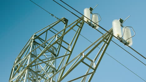 Close-up-of-insulators-on-electrical-pylon,-blue-sky-background