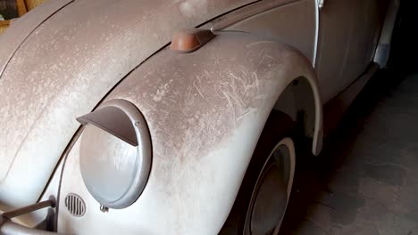 Front-side-view-of-dirty-white-car-hood-standing-in-garage