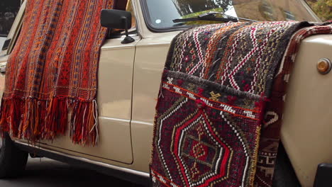 Low-angle-view-of-colourful-rugs-draped-over-side-of-car-and-bonnet-in-Yerevan,-Armenia