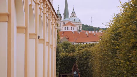 Pan-Down-Reveal-Of-Female-Tourist-Walking-Beside-Hedge-At-Waldstein-Gardens-In-Prague